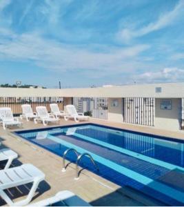 a pool on the roof of a hotel with chairs and a building at Flat Palladium in São Vicente