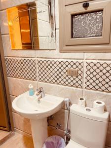 ein Badezimmer mit einem Waschbecken, einem WC und einem Spiegel in der Unterkunft El mansour hotel apartmen 91 in Mansoura