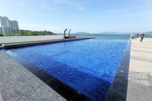 a pool with blue water next to the ocean at b.suites 21 in Kota Kinabalu