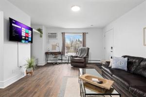 ein Wohnzimmer mit einem Ledersofa und einem Flachbild-TV in der Unterkunft Brand New 1BR Flat, Cozy King Suite in Mount Clemens