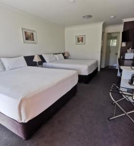 a hotel room with two beds and a desk at Gallery Motel in Murwillumbah