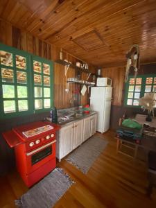 eine Küche mit einem roten Herd und einem Kühlschrank in der Unterkunft Morada Vale das Águas in São Bonifácio