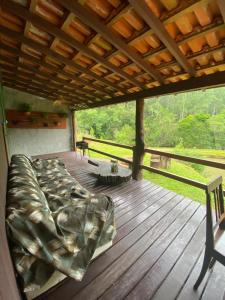 a bed on a wooden deck with a roof at Morada Vale das Águas in São Bonifácio