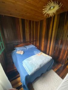 ein Schlafzimmer mit einem Bett in einem Holzzimmer in der Unterkunft Morada Vale das Águas in São Bonifácio