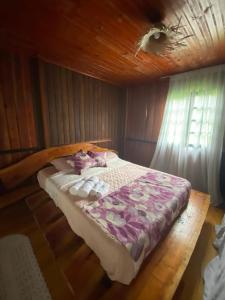 a bed in a room with a wooden ceiling at Morada Vale das Águas in São Bonifácio