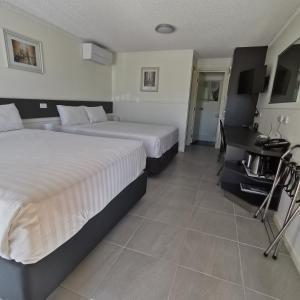 a hotel room with two beds and a desk at Gallery Motel in Murwillumbah