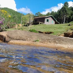 ein Haus auf einem Hügel neben einem Fluss in der Unterkunft Morada Vale das Águas in São Bonifácio