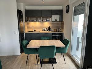 kuchnia z drewnianym stołem i zielonymi krzesłami w obiekcie Gorgeous Apartment near Paris & Disneyland w mieście Fontenay-sous-Bois