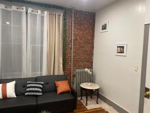 a living room with a black couch and a brick wall at F.M.T. in Harrisburg