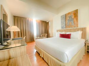 a bedroom with a large white bed and a television at Grand Zuri Dumai in Dumai