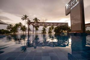 una piscina en un complejo con palmeras en Netuanah Praia Hotel, en João Pessoa