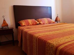 een slaapkamer met een bed met een oranje deken en 2 lampen bij DUNES DE MARTIL in Martil