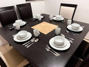 a black table with white plates and silverware on it at Casa a 3 Min del Consulado in Ciudad Juárez