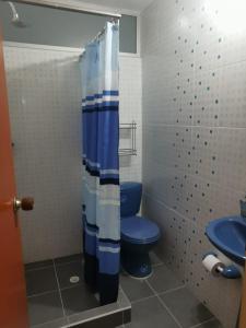 La salle de bains est pourvue de toilettes bleues et d'un rideau de douche. dans l'établissement Habitaciones en Acogedora estancia en pleno centro de Ibagué, à Ibagué