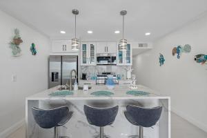 a kitchen with a island with three blue bar stools at Welcome to Sea Forever - Balcony Water View Tampa in Tampa
