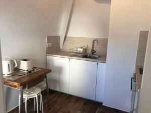 una pequeña cocina con armarios blancos y fregadero en Appartement Villers-sur-Mer, 1 pièce, 2 personnes - FR-1-712-3, en Villers-sur-Mer