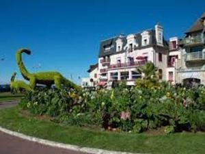 ein Gebäude mit einer Dinosaurierstatue vor einem Garten in der Unterkunft Appartement 2 pièces cosy au centre-ville, à 2 pas de la plage avec parking - FR-1-712-35 in Villers-sur-Mer