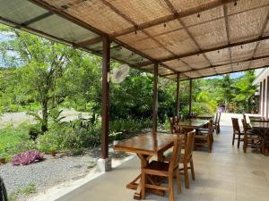 un patio con mesas y sillas bajo una pérgola en Miotrakasa, en Cahuita