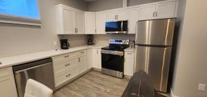 a kitchen with white cabinets and a stainless steel refrigerator at ChessKings Executive Suite - 2 Bedrooms in Winnipeg