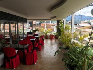 a restaurant with red chairs and tables and plants at Hotel Bolivariano in Ibagué