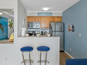 une cuisine avec deux tabourets bleus à un comptoir dans l'établissement Paradise Beach Sailport Resort Condo, à Tampa