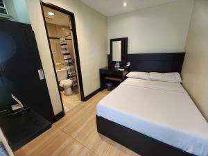 a bedroom with a large white bed and a bathroom at Green Glass Hotel in Calamba