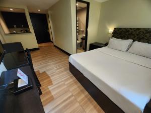 Un dormitorio con una cama grande y una mesa con un libro en Green Glass Hotel, en Calambá
