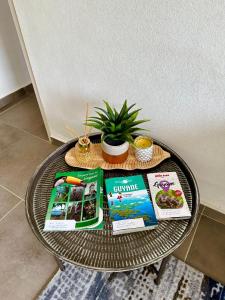 una mesa de café con libros y una planta en ella en La Villa Louisia en Matoury