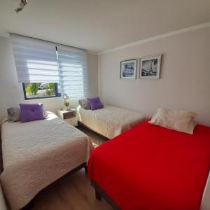 1 dormitorio con 2 camas y manta roja en Depto nuevo 3 a 4 personas, en Viña del Mar