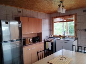 a kitchen with a stainless steel refrigerator and a table at Cabañas Lomas de Ten Ten in Castro