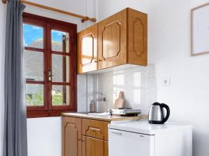 cocina con armarios de madera y nevera blanca en Almyra Villa, en Perissa