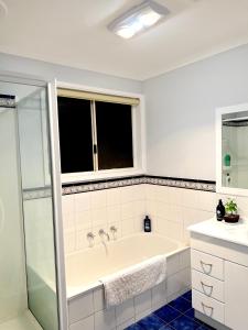 baño blanco con bañera y ventana en Apple House Hoppers Crossing, en Tarneit