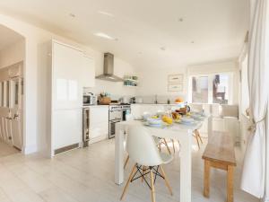 a white kitchen with a white table and chairs at Southern Bell in South Hayling