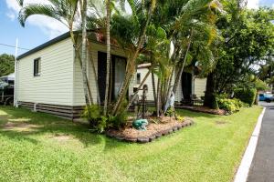 a house with palm trees in front of it at Sarina Palms Caravan and Cabins Village in Sarina