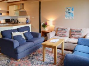 a living room with two blue couches and a table at Jasmine Cottage in Scalby