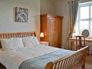 a bedroom with a bed and a desk and a window at Dunley Farmhouse in Bovey Tracey