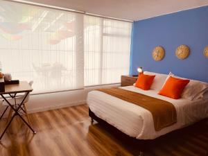 a bedroom with a bed with orange pillows and a window at CASA CREAZZO 62 - Movistar Arena, Vive Claro in Bogotá