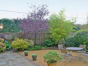 a garden with a table and chairs and a fence at The Barn in Ropley