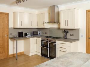 a kitchen with white cabinets and a stove top oven at Seascape in Mainsriddle