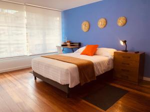 - une chambre avec un lit et un mur bleu dans l'établissement CASA CREAZZO 62 - Movistar Arena, à Bogotá