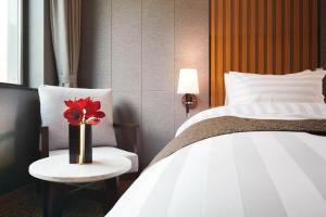 una habitación de hotel con una cama y un jarrón con una flor roja en Jeongseon Intoraon Hotel en Jeongseon