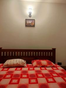 a bedroom with a bed with a red and white quilt at Kalyani Homestay in Kodaikānāl