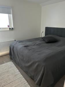 un letto in una camera bianca con una coperta nera di TunnebergaBoB a Jonstorp