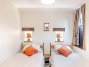 Duas camas num quarto com paredes brancas e almofadas laranja em Poppies Court Jericho Farm em Earl Sterndale