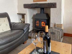 a bottle of wine and two glasses on a table in front of a fireplace at Trevena Star in Rosedale Abbey