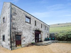 a stone building with a red door and windows at Poppies Court Jericho Farm in Earl Sterndale