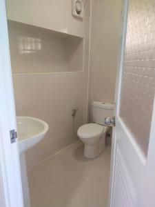 a white bathroom with a toilet and a sink at Rock sand Resort in Trat