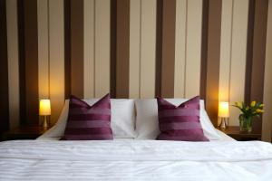a bed with purple and white pillows and two lamps at 10 Bed And Breakfast in Poznań