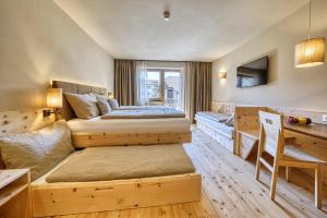 a bedroom with two beds and a desk at Eco Bnb & Apartments Bründlerhof in Marlengo