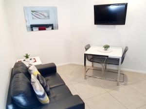 a living room with a black leather couch and a table at M5 West Perth Studio Apartment near Kings Park in Perth